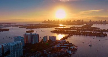 Parlak batan güneş şehrin manzarasını ve su manzarasını aydınlatıyor. Biscayne Körfezi üzerinde güzel bir günbatımı, Miami, ABD. Hava görünümü.