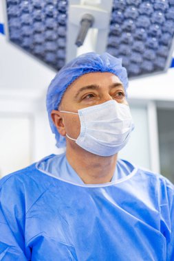 Cerrah ameliyathanede, ameliyat ışıkları altında. Steril ortamda prosedür için hazırlanmış klinik profesyoneli