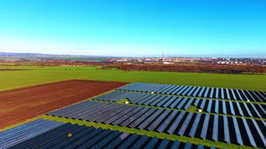 Birden fazla güneş panelinin üzerindeki görüntüler güneş ışığını emiyor. Bölgeyi çevreleyen yeşil alanlar. Dev bir petrol rafinerisinin bölgesine yaklaşıyoruz..