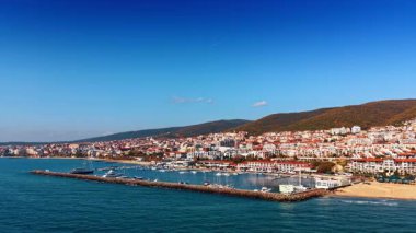 Baraj boyunca mavi suların üzerinden ve teknelerle rıhtımların üzerinden uçmak. Güneşli bir günde Bulgaristan 'ın tatil beldesine hava perspektifi.