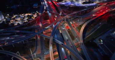 Yan yana giden otoyollarda farları açık bir araç. Geceleri yoğun kavşağa hava perspektifi.