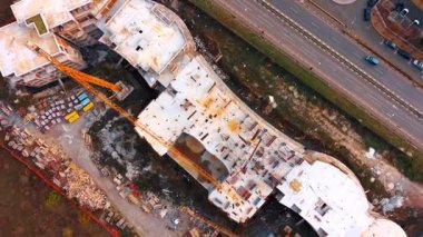 İnşaat halindeki binanın çatısında daireler çiziyor. Yapının etrafına bir sürü enkaz saçılmış. Binanın üzerinde bir vinç duruyor..