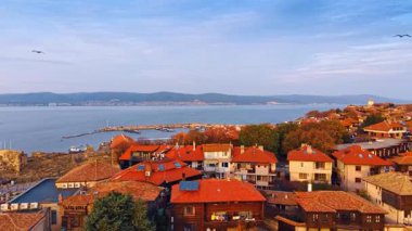 Bulgaristan 'ın Nessebar kentindeki sahil parkındaki evlerin kırmızı kiremitli çatıları. Rıhtıma yanaşıyor. Bir sürü tekne ve yatla..