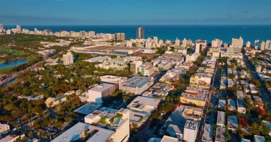 Parlak güneşle parıldayan yemyeşil manzaralı muhteşem bir şehir. Miami, ABD 'nin insansız hava aracından muhteşem manzarası. Arkaplanda mavi geniş su manzarası.