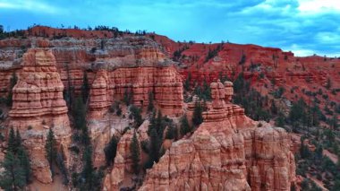 Bryce Canyon Ulusal Parkı 'nın çarpıcı jeolojik oluşumları, Utah, ABD. Arka plandaki kırmızı kayaların arkasındaki bulutlu gökyüzü.