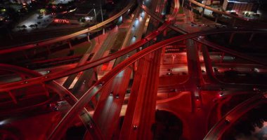 Kırmızı ışıkla işaretlenmiş çok katlı bir kavşak. Geceleri kavşaktaki yoğun yollar. İnsansız hava aracı görüntüleri.