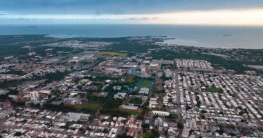 Kasvetli bir günde havadan bakıldığında, alçak katlı bir şehir manzarası. Karanlık bulutlar arka planda su manzarasıyla birleşir. Porto Riko.