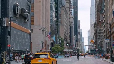 New York, ABD, 12 Ağustos 2025: Yüksek binaları olan ünlü Beşinci Cadde. Birçok araba caddenin yanından geçiyor ve insanlar kaldırımdan yürüyor. New York, ABD.