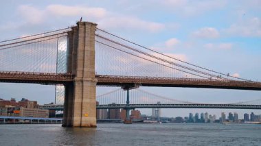 Gün batımında Brooklyn Köprüsü 'nden bir nakliye aracı geliyor. Nehir manzarasının ünlü New York simgesine bakın..