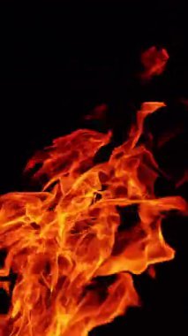 Havaya yükselen kızgın ateş. Gece büyük bir kamp ateşi yanıyor. Kapatın. Dikey video