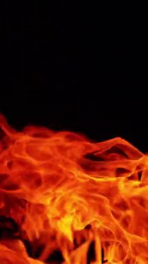 Sağa doğru hareket eden büyük alev dilleri. Geceleri ateş yanıyor. Kapatın. Dikey video