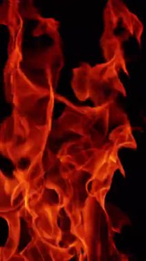 Kızıl alevler gece yanar. Karanlıkta yalıtılmış hareket eden kamp ateşi dillerinin yakın görüntüsü. Kapatın. Dikey video