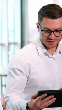 Geniş ofiste kahve molası. Erkek ve kadın ayrı odada aletlerle durup içki içiyorlar. Dikey video