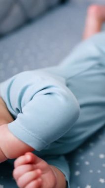 Karyolasında sevimli minik bir çocuk. Sevimli bebek ağzında bir emzik tutuyor ve yana yuvarlanıyor. Kapatın. Dikey video