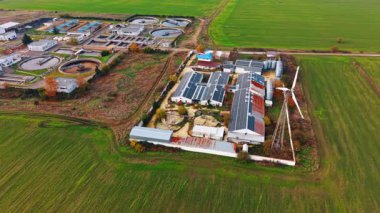 Çatılarda güneş panelleri olan uzun depolara yaklaşıyoruz. Modern atık su arıtma tesisi yakınlarındaki sanayi tesisleri. Hava görünümü.
