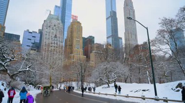 New York, ABD, 19 Aralık 2025: Çok sayıda insan New York, ABD 'de karla kaplı Central Park' ta vakit geçiriyor. Manhattan 'ın alçak açılı manzarası arka planda yükseliyor.