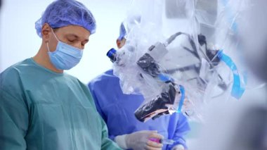 Kafkas sinir cerrahı elektrikli aletleri bir kenara koyuyor. Ameliyat hemşiresi mikroskop başında duran bir cerraha başka bir cihaz verdi..