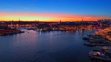 Geceleri muhteşem Stockholm, İsveç rıhtımları. Sokak lambaları açık parlayan şehir. Arkaplanda güzel turuncu gökyüzü.