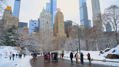 New York, ABD, 19 Aralık 2025: Yoldan geçenler ve çekçekçekçekler kardan temizlenmiş asfalt yolda hareket ediyorlar. New York, ABD 'de güzel bir kış. Manhattan yüksek binaları arka planda.