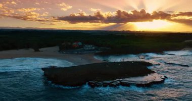 Gün batımında kumlu sahil boyunca. Çalkantılı su manzarası kıyıya vuruyor. Hava görüntüsü. Porto Riko.