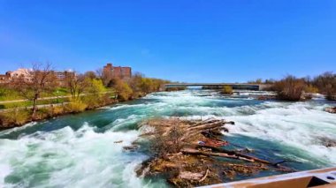 Amerika 'daki Niagara Şelalesi Eyalet Parkı' ndaki Amerikan Şelalesi Rapids 'i. Kanada tarafına bakıyor. Arkaplanda açık mavi gökyüzü.