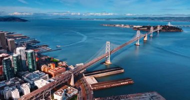 Oakland Bay Köprüsü 'ne yoğun bir trafik varken yaklaşıyoruz. Nehir teknesi arka plandaki rıhtıma gidiyor. San Francisco, California, ABD.