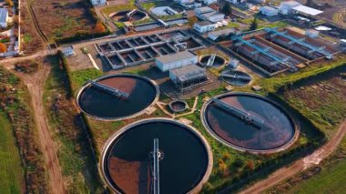 Bu sahnede bir atık su arıtma tesisi ve karanlık suyla dolu birkaç büyük dairesel tank var..