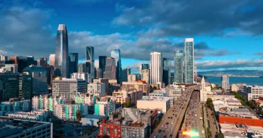 Şehir merkezinde yoğun trafik varken iki katlı otoyollarda yükseliyor. Bulutlu gökyüzüne karşı gökdelen ufuk çizgisinin alçak açısı. San Francisco, CA, ABD.