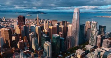 En yüksek gökdelenlerin tepesine doğru ilerliyoruz. San Francisco şehir merkezindeki Satış Gücü Kulesi, CA, ABD. Su manzarası üzerinde dramatik bulutlar..