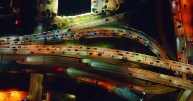 Büyük kavşakta çok sayıda araba iyi ışıklandırılmış otobanlardan geçer. Gece vakti Los Angeles 'a gidip geliyor. Hava görünümü.