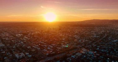 Güneşin batışı modern bir şehrin manzarasını kamaştırıyor. Otobanlarda birden fazla araba hareket ediyor. Günbatımı Los Angeles, Kaliforniya, ABD 'de. Hava görünümü.