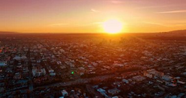 Trafiğin yoğun olduğu çok şeritli otoyollara yaklaşıyoruz. Batan güneş, Los Angeles, Kaliforniya, ABD 'nin şehir manzarasını aydınlatıyor. Hava görünümü.