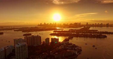 Suyun üzerinden uçmak, parlak batan güneş tarafından aydınlatılır. Brickell Key 'in altın saat manzarası. Miami, Florida, ABD.