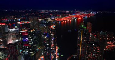 Miami, ABD, 4 Ağustos 2025: Miami, Florida, ABD 'deki gökdelenlerin muhteşem tasarımı. İnsansız hava aracı gece şehre iniyor. Arkaplanda koyu su manzarası.