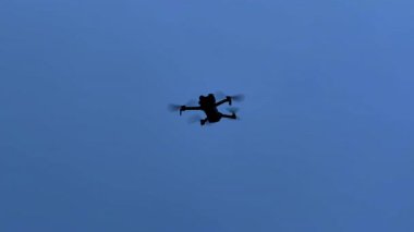 İnsansız hava aracı gün batımında bir şehrin yakınlarında gökyüzünde uçuyor. Bir insansız hava aracı şehrin üzerindeki alacakaranlıkta gökyüzünde uçar..