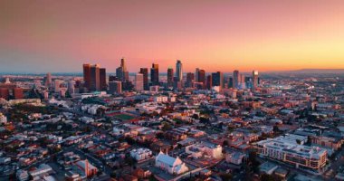 Metropolis 'in yüksek silueti pembe gökyüzüne karşı. Los Angeles, Kaliforniya 'daki gökdelenlere yaklaşan insansız hava aracı görüntüleri..