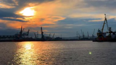 Limanda gün batımında, akşamları vinçler ve gemilerle birlikte. Gün sona ererken, güneş vinçlerin ve gemilerin arkasında batar..