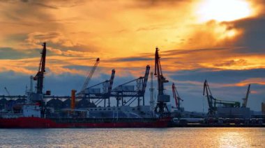 Günbatımında limandaki gemiler ve turnalar akşam renkli gökyüzüyle. Büyük gemiler ve turnalar bir limanda görülür. Akşam gökyüzünde güneş batarken. Renklerle dolu..