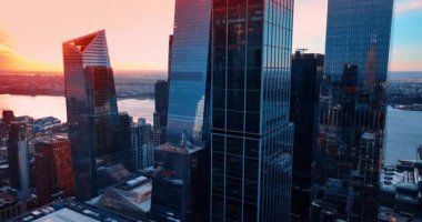 New York, ABD 'nin görkemli cam gökdelenleri boyunca yükseliyor. Batan güneş arka planda gökyüzünü aydınlatıyor. Hava görünümü.