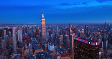 Batan güneşin ışığında Empire State Binası 'nın çarpıcı binasına yaklaşıyoruz. Hava perspektifi alacakaranlıkta New York 'un aydınlık sokaklarında.