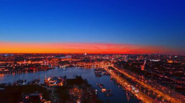 İsveç 'in modern Stockholm şehrinin geceleri ışıkları açık olan muhteşem manzarası. İnanılmaz turuncu ve mavi gökyüzü şehrin üzerinde.