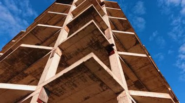 Gelecekteki binanın köşesinde yükseliyor. Mavi gökyüzüne karşı yapının çerçevesinde düşük açı görünümü.