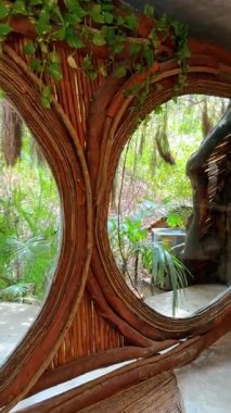 Büyük yuvarlak pencereler ahşap ve ahşap süslemeli büyük taş masa. Tulum, Meksika 'daki güzel Azulik Resort' un içinde. Dikey video.