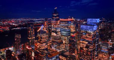 New York, ABD 'nin modern cam gökdelenlerinin camları açık. Nehrin karanlık çizgisi gece şehrin manzarasını geçiyor. Hava görünümü.