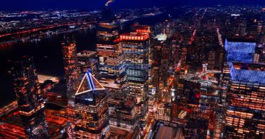 Nehir kıyısındaki parlak gökdelenlere yaklaşıyoruz. İnsansız hava aracından hiç uyumayan metropolün gece manzarası.