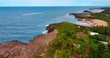 Mavi denizin kayalık kıyılarına uçuyor. Bir motorlu tekne su manzarası boyunca hareket ediyor. Porto Riko.