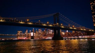 Manhattan Köprüsü gece manzarası. Manhattan Köprüsü nehir boyunca uzanır. Geceleri parlayan şehir silüeti ile..