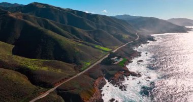 Fantastik dağ sırası boyunca otobanlardan çok az araba geçer. Okyanus dalgaları kayalık kıyıya vurdu. İHA 'dan Big Sur, California, ABD' ye manzara.