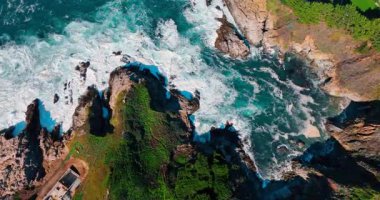 Şiddetli dalgalar güneşli bir günde kayalık kıyıya vurur. Büyük Sur, California, ABD 'nin pitoresk sahillerindeki evlerin görüntüleri.