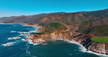 Kaliforniya, Big Sur 'daki Bixby Köprüsü' ne yaklaşıyoruz. Güneşli bir günde kayalık sahilin manzarası.
